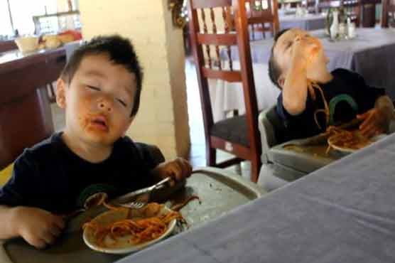 Twins trying to stay awake to finish their spaghetti