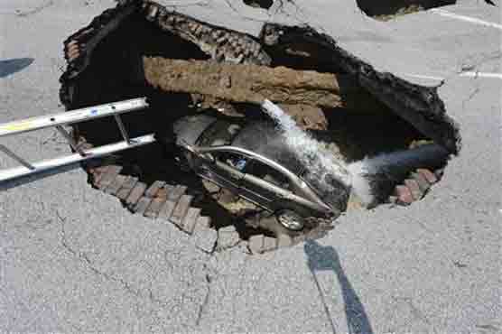 Sinkhole swallows car, driver climbs out
