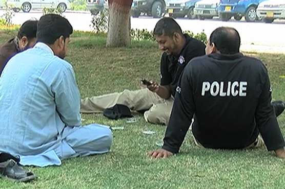Lack of interest: On duty policemen pass time by playing cards in Karachi