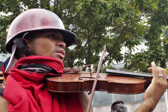 Venezuelan protester plays violin in face of tear gas shells