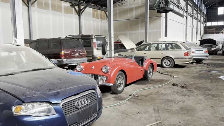 Abandoned warehouse with car graveyard of Rolls-Royces, Land Rovers and BMWs