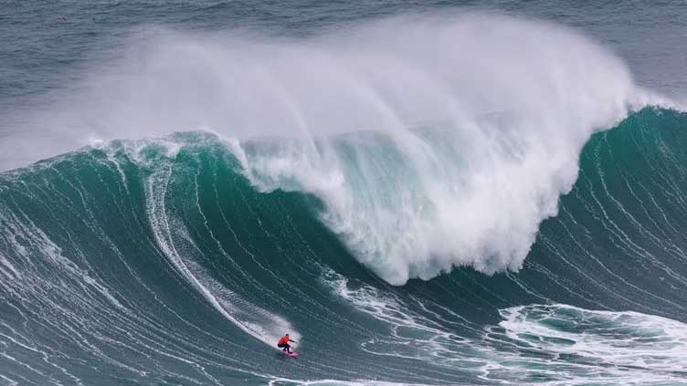 Surfers take on giant waves in Nazare as extreme weather hits Europe