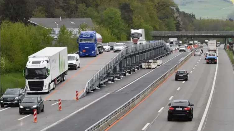 Mobile bridge allows workers to pave roads without halting traffic