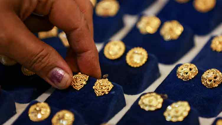 Gold retreats from near four-week peak as dollar ticks up